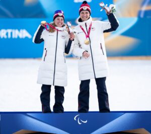Carina Edlingerová s&nbsp;trasérem Alexandrem Paťavou na paralympijských stupních vítězů. Zdroj: Český paralympijský výbor, autor: Matěj Nový