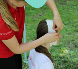 Soutěžící ošetřuje hlavu figuranta a&nbsp;obvazuje ránu na hlavě.